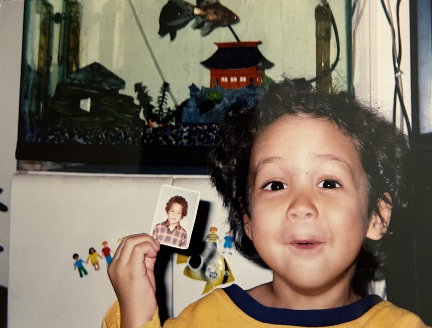 A small child holding up a photograph of another small child